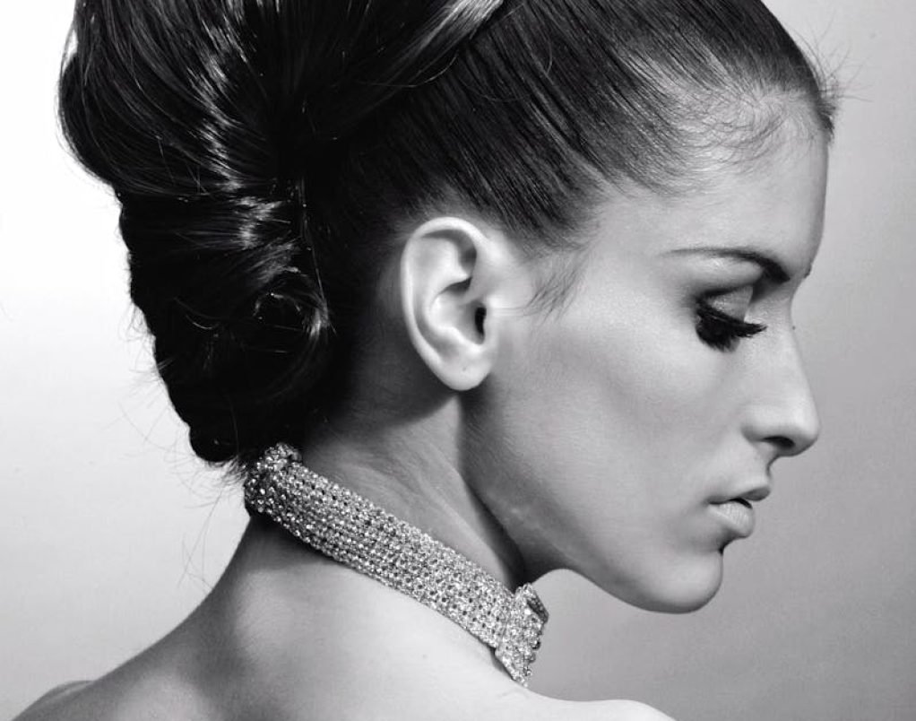 Graceful profile portrait of a woman with elegant hairstyle and necklace.